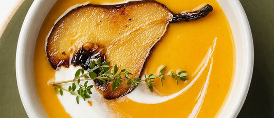 Sopa de calabaza Rezuma servida en bowl blanco con crema y hierbas, junto al packaging"